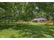 Lush, green backyard featuring mature trees, a playset, and a storage shed at 9014 Holliday Dr, Indianapolis, IN 46260