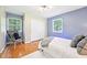 Inviting bedroom with hardwood floors, blue walls, and a cozy chair by the window at 9014 Holliday Dr, Indianapolis, IN 46260