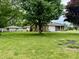 View of a well-maintained brick home showcasing a spacious front yard with mature trees at 9099 Ne Oak St, Alexandria, IN 46001