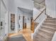 Bright foyer with hardwood floors, staircase, and decorative glass door leading to a living space at 9834 Belcrest Ln, Indianapolis, IN 46256