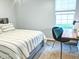 Bright bedroom features a bed with striped bedding, a desk and chair, and a sunny window at 10421 Sand Creek Blvd, Fishers, IN 46037