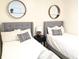 Charming bedroom featuring two twin beds with stylish grey headboards and decorative round mirrors at 10421 Sand Creek Blvd, Fishers, IN 46037
