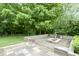 View of a lush green back yard with a built in stone patio area and manicured greenery at 11036 Ravenna Way, Indianapolis, IN 46236