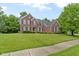 Beautiful two-story brick home featuring black shutters, a well-kept lawn, and lush landscaping at 11036 Ravenna Way, Indianapolis, IN 46236