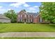 Traditional brick home with a well-manicured lawn and mature trees showcases classic American architecture at 11036 Ravenna Way, Indianapolis, IN 46236
