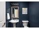 Stylish half bathroom features a pedestal sink, decorative mirror, and dark blue walls at 1237 Wolcott Ct, Westfield, IN 46074