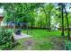 Lush backyard with a stylish pergola over a stone patio with a fire pit, and a shed surrounded by mature trees and green grass at 1264 Black Oak Dr, Greenwood, IN 46143