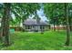 Expansive backyard featuring a covered patio, lush green lawn, mature trees, and a charming fire pit with seating at 1264 Black Oak Dr, Greenwood, IN 46143