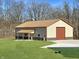 A spacious barn with a red roof, light siding and two garage doors sits on a green lawn at 1412 10Th St, Danville, IN 46122