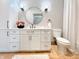 Well-lit bathroom showcasing white cabinets, a round mirror, and a toilet with a travertine tile floor at 1412 10Th St, Danville, IN 46122