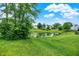 Scenic view of a well-manicured backyard leading to a serene pond, surrounded by mature trees at 15523 Follow Dr, Noblesville, IN 46060