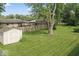 Large backyard boasts a well-maintained lawn, mature trees, privacy fence, and a storage shed at 1613 Park Rd, Anderson, IN 46011