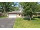 Single-story home with stone facade, attached garage and asphalt driveway with mature front yard landscaping at 1613 Park Rd, Anderson, IN 46011