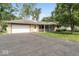 Charming single-story home with stone facade, attached garage, mature trees, and spacious front yard at 1613 Park Rd, Anderson, IN 46011