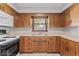 Galley-style kitchen with wood cabinets, appliances, and tiled flooring at 1613 Park Rd, Anderson, IN 46011