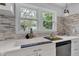 Kitchen sink featuring stone backsplash, stainless dishwasher, and a view of backyard trees through the double window at 1618 Villa Ave, Indianapolis, IN 46203