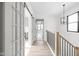 Hallway with wood floors, modern light fixtures, wood railing and view of open rooms through glass doors at 1654 Fernley Dr, Westfield, IN 46074