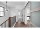 Upstairs hallway featuring hardwood floors, modern light fixture, and sliding door leading to the kitchen at 1655 Carrollton Rail Dr, Westfield, IN 46074