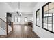 Open concept living room view with wood floors, black-trimmed windows, and an open staircase at 1655 Carrollton Rail Dr, Westfield, IN 46074