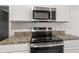 A kitchen features stainless steel appliances, white cabinetry, and granite countertops at 2270 Collins Way, Greenfield, IN 46140