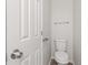 Well-lit powder room with a toilet, towel bar, and a white door at 2270 Collins Way, Greenfield, IN 46140