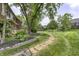 Wide view of a home's backyard featuring mature trees, grassy areas and stone pathway at 2553 Forest Hills Blvd, Greenwood, IN 46143