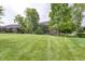 Open backyard featuring green lawn and trees, extending from a brick house at 2553 Forest Hills Blvd, Greenwood, IN 46143