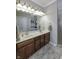 Bathroom showcasing a dual-sink vanity with wood cabinetry, framed mirrors, and a tiled shower with a glass door at 2553 Forest Hills Blvd, Greenwood, IN 46143