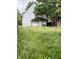 View of the backyard with overgrown grass and a small outbuilding at 319 S Temple Ave, Indianapolis, IN 46201