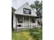 Exterior front view of a two-story home with a small porch and overgrown landscaping at 319 S Temple Ave, Indianapolis, IN 46201