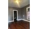 Empty living room with hardwood floors, brown walls, and natural light from a window at 319 S Temple Ave, Indianapolis, IN 46201
