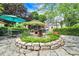 Lush backyard featuring a stone patio with a fountain, umbrella-shaded table, and charming landscaping at 3317 S 100 E, Greenfield, IN 46140