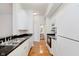 Narrow kitchen view with white appliances, wooden floor, granite countertops and white cabinets at 355 E Ohio St # 209, Indianapolis, IN 46204
