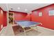 Ping pong table area in the finished basement with bright red walls and recessed lighting at 4017 Ivory Ct, Carmel, IN 46074