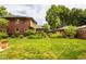 A lush backyard with a manicured lawn, garden, and charming brick architecture at 4415 N Illinois St, Indianapolis, IN 46208