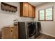 Functional laundry room with modern appliances, upper cabinets, and natural light from the window at 4415 N Illinois St, Indianapolis, IN 46208