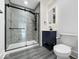 Modern bathroom with glass shower, vanity with storage, and gray wood-look flooring at 4923 E University Ave, Indianapolis, IN 46201