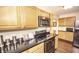 Kitchen with stainless appliances, wood cabinets and black countertops at 5024 N Kenwood Ave, Indianapolis, IN 46208