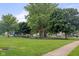 Green common area with mature trees, playground, swing set, and picnic tables for residents to enjoy at 6227 Long River Ln, Indianapolis, IN 46221