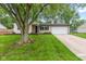 Charming single-story home featuring an attached garage, mature trees, and a well-maintained lawn at 6310 Kellum Dr, Indianapolis, IN 46221