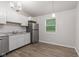 Bright kitchen features white cabinetry, stainless steel appliances, gray countertops, and wood-look flooring at 6310 Kellum Dr, Indianapolis, IN 46221