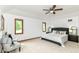 This primary bedroom features a carpeted floor, a ceiling fan, three windows and an upholstered headboard at 7220 Normandy Way, Indianapolis, IN 46278