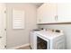 Well-lit laundry room featuring a front-load washer and dryer, bright white cabinets, and light-colored wood-look floors at 8263 Bryce Blvd, Pendleton, IN 46064