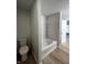 Bright bathroom shows white tub and toilet with light wood flooring and an open door at 832 Spinney Ln, Whiteland, IN 46184