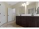A bathroom featuring double sinks with dark wood cabinets, neutral walls, and tiled floors at 11393 Muirfield Trce, Fishers, IN 46037