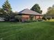 Side exterior of brick home features a well-maintained lawn and mature trees at 1201 Briarwood Dr, Brownsburg, IN 46112