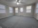 Spacious living room with several windows, neutral gray walls, new carpet, and modern ceiling fan at 1201 Briarwood Dr, Brownsburg, IN 46112