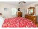 Bedroom featuring a red floral comforter, hardwood floors, and bright natural lighting at 12014 Briar Way Center Dr, Indianapolis, IN 46126