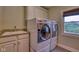 Bright laundry room featuring a washer and dryer set, sink with granite counters, and a window for natural light at 13429 Boxelder Ct, Carmel, IN 46074