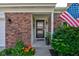 A welcoming front porch with an American flag, brick facade, and blooming flowers at 1510 Dominion Dr, Zionsville, IN 46077